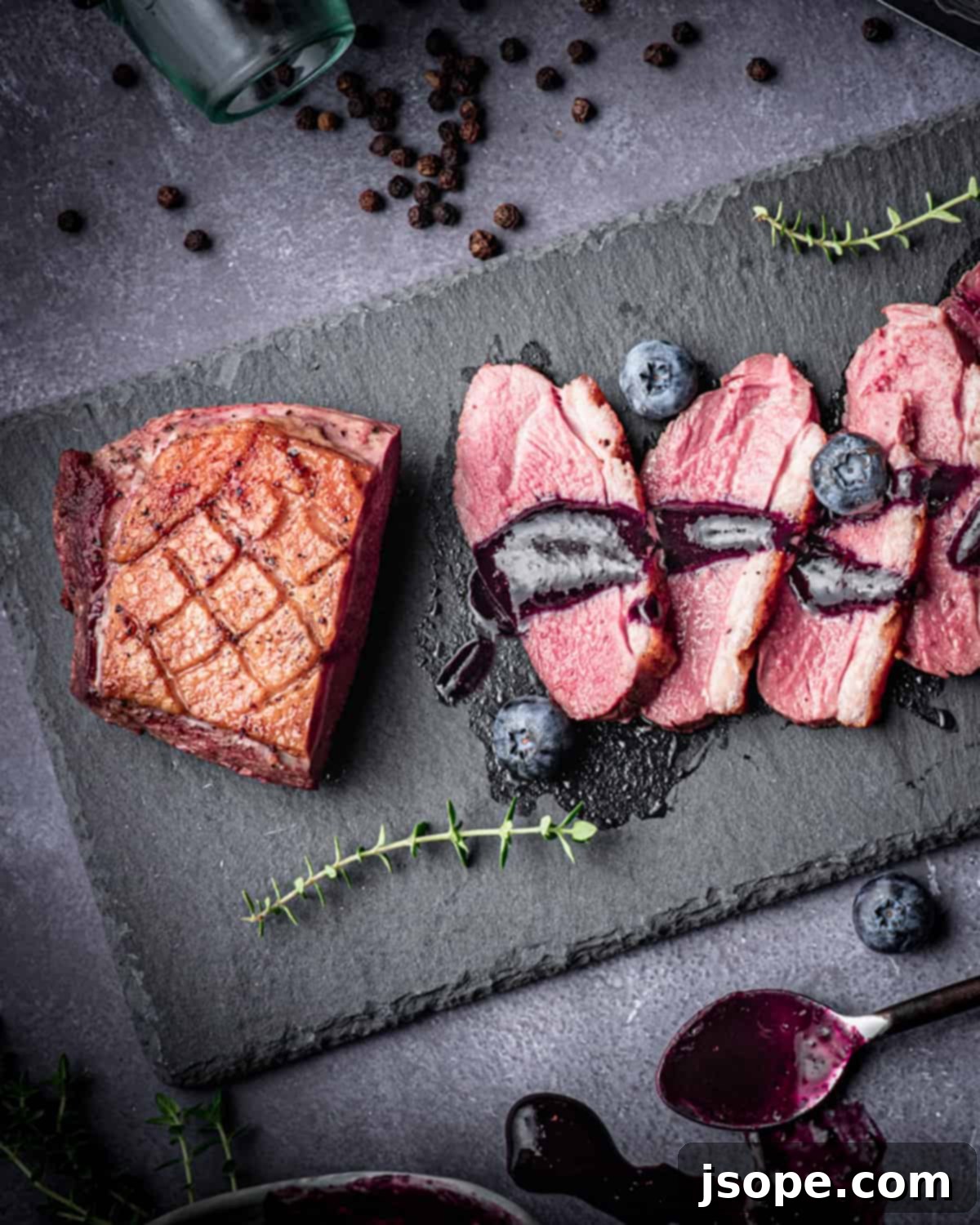 Blueberry Thyme Red Wine Reduction over pan seared duck breast, showcasing the rich color and texture.