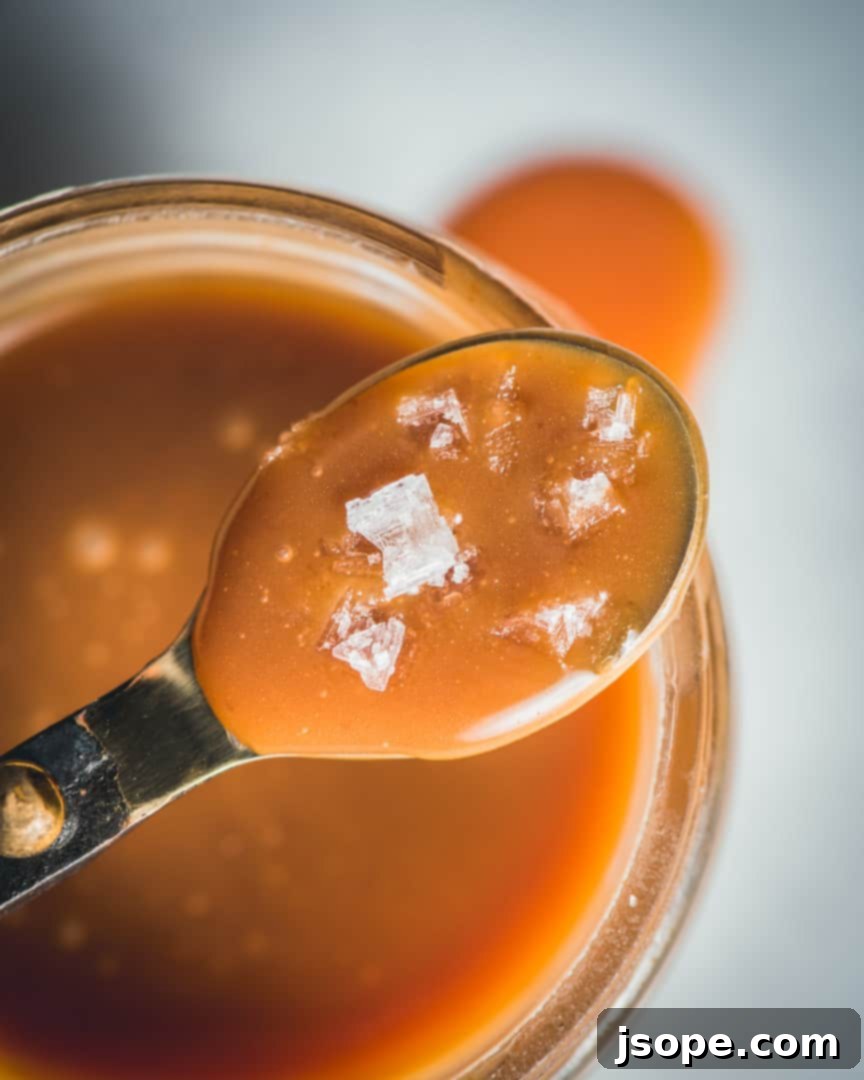 Brown Butter Bourbon Carmel Sauce with flaky sea salt, showing a close-up of the sauce in a jar.