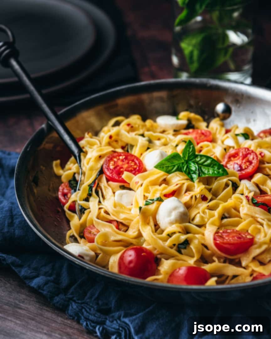Delicious and fresh Summer Pasta (Pasta d'estate) served in a bowl, garnished with basil and parmesan