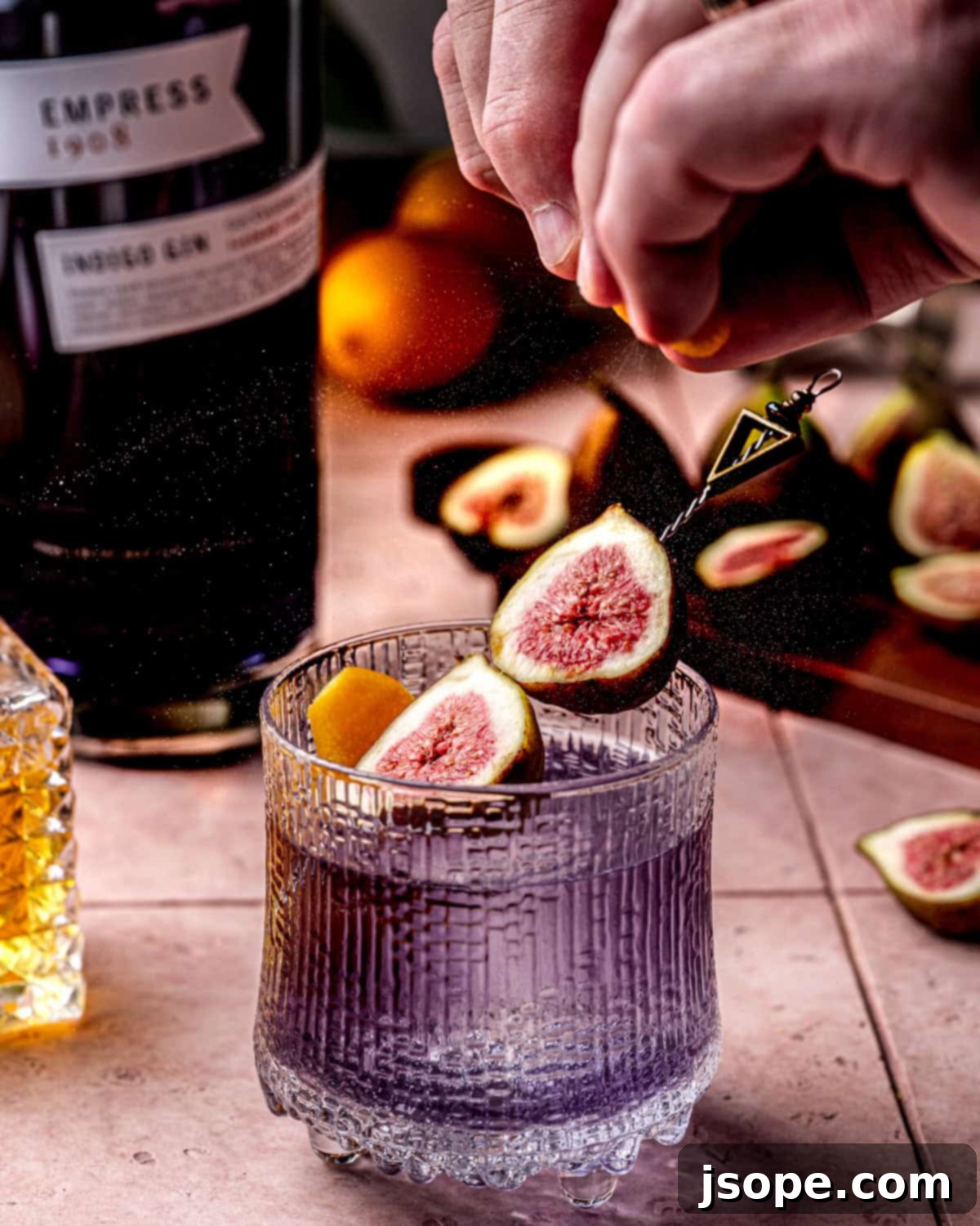 Meyer lemon zest spritz onto a fig cardamom gin old fashioned