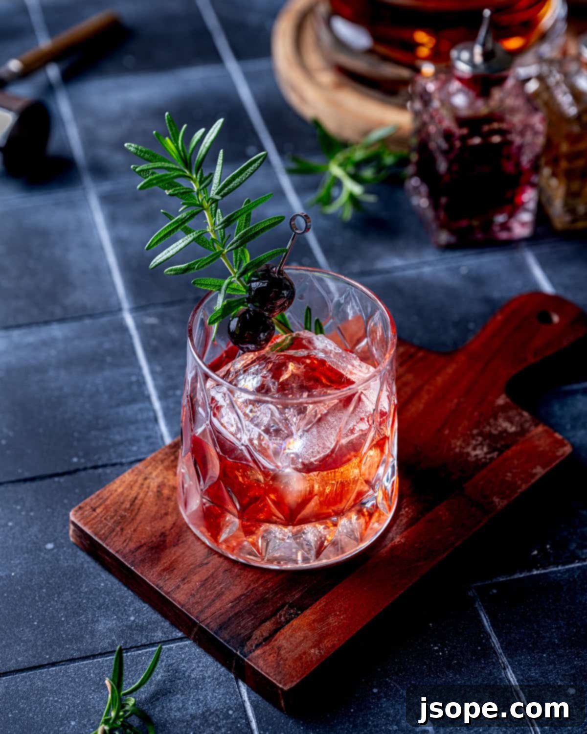 Spiced Cranberry Old Fashioned cocktail in a rocks glass with garnishes.