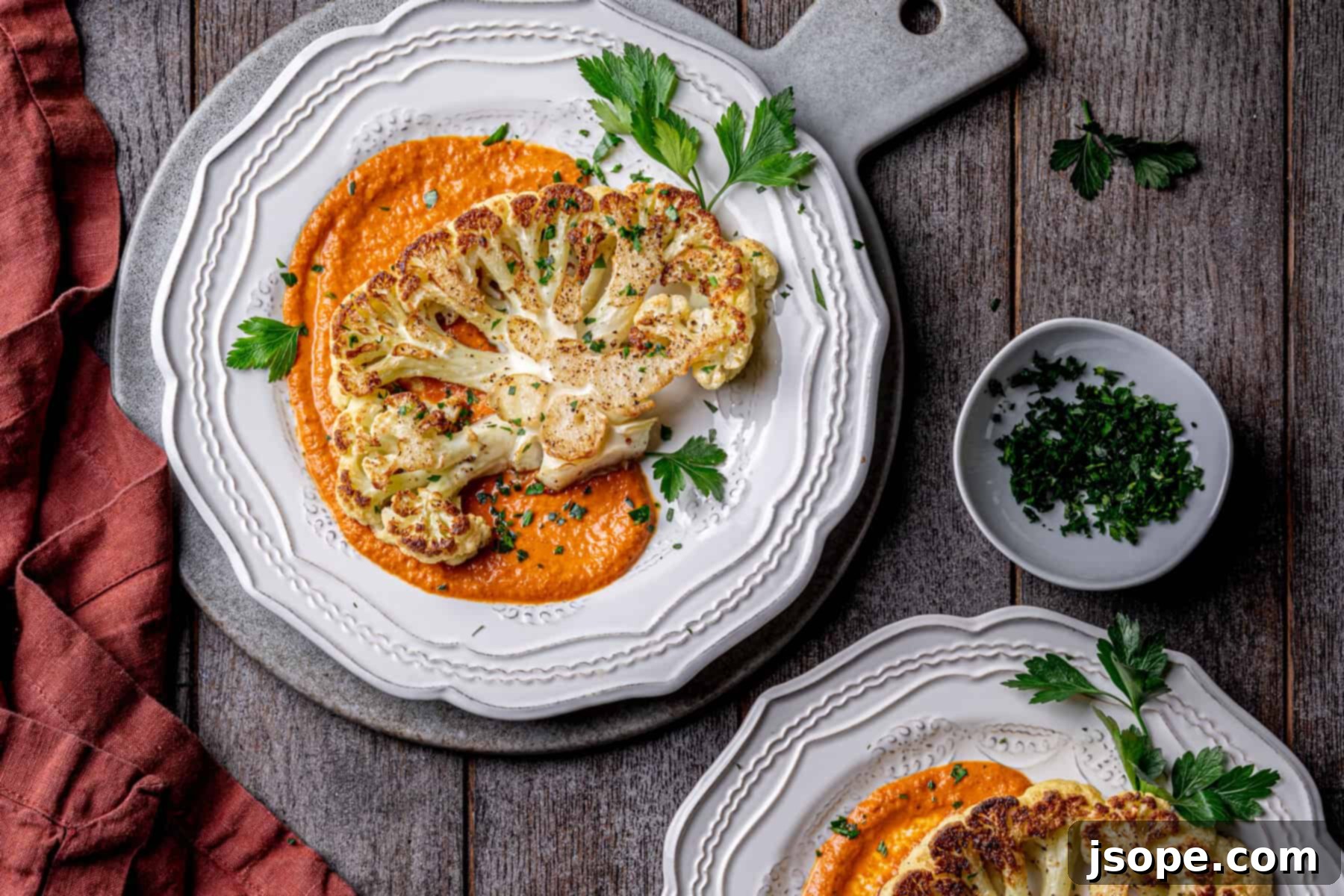 Large platter of roasted cauliflower steaks with a bowl of romesco sauce