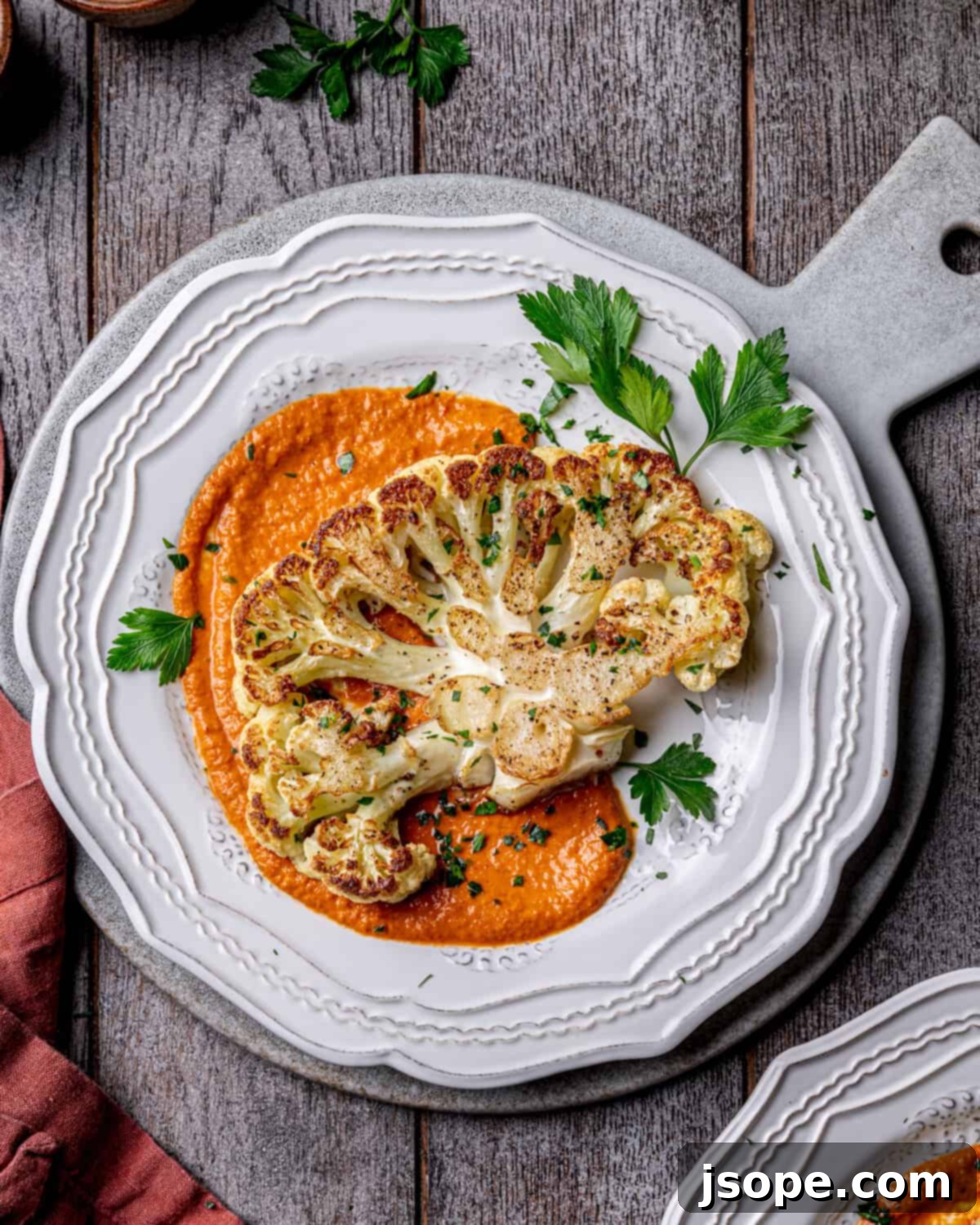 Close-up of roasted cauliflower steaks with romesco sauce and fresh herbs