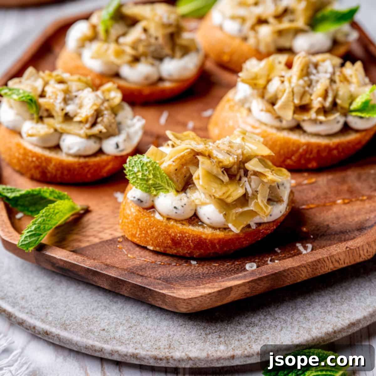Marinated artichoke hearts crostini, a delightful Italian appetizer with whipped ricotta and goat cheese on toasted baguette.