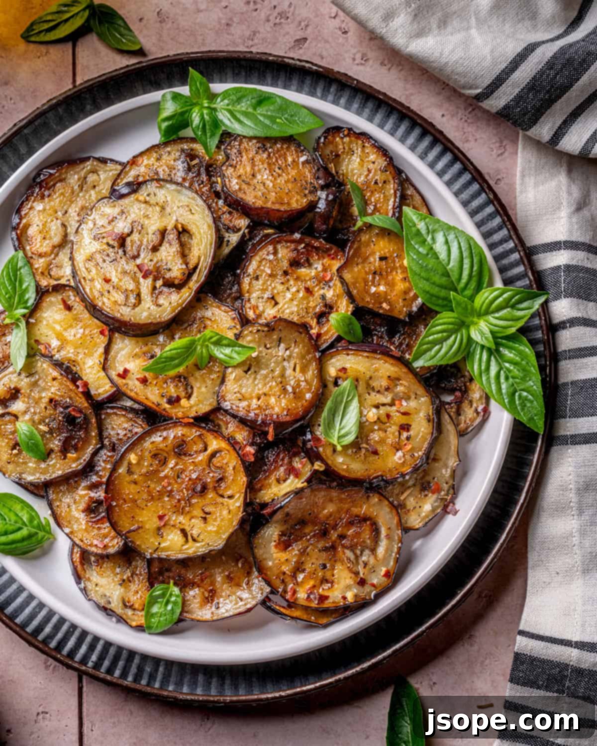 Close-up of golden brown Sautéed Italian Eggplant slices garnished with fresh basil