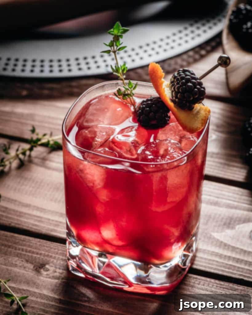 Blackberry Thyme Reimagined 2 Blackberry Thyme New Fashioned cocktail with a dark background, garnished with fresh blackberries and a sprig of thyme