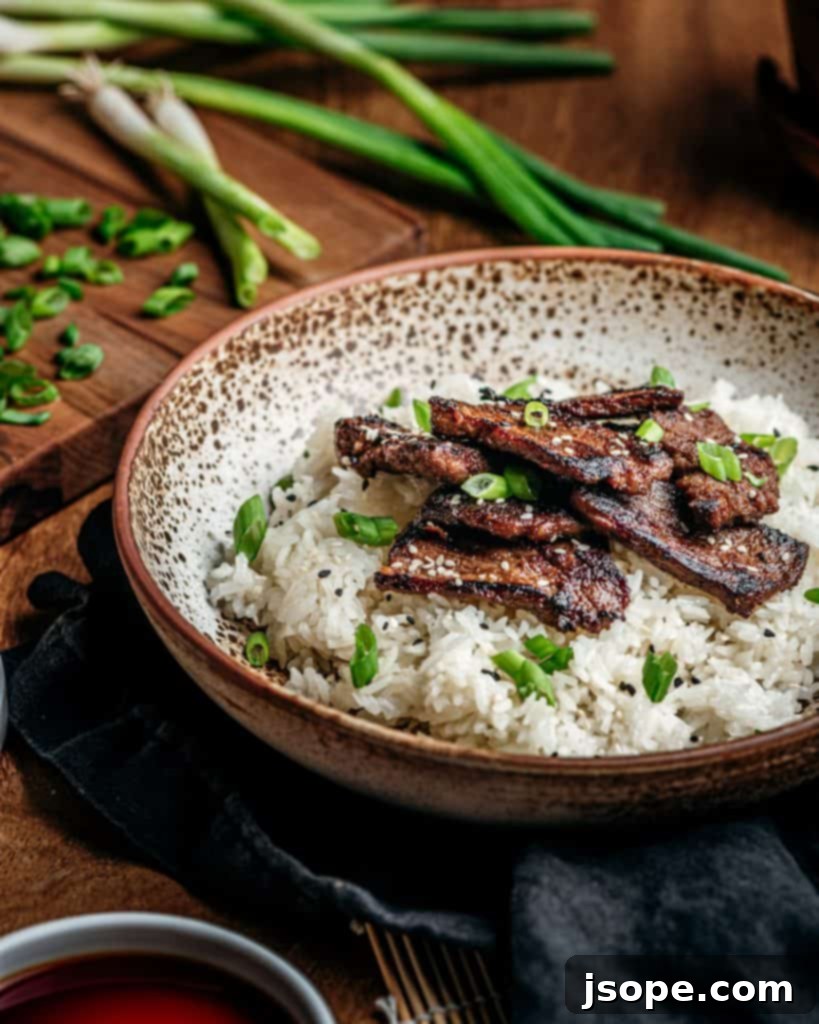 Plated Thai Spiced Boneless Short Ribs over sticky rice, garnished with green onions and sesame seeds
