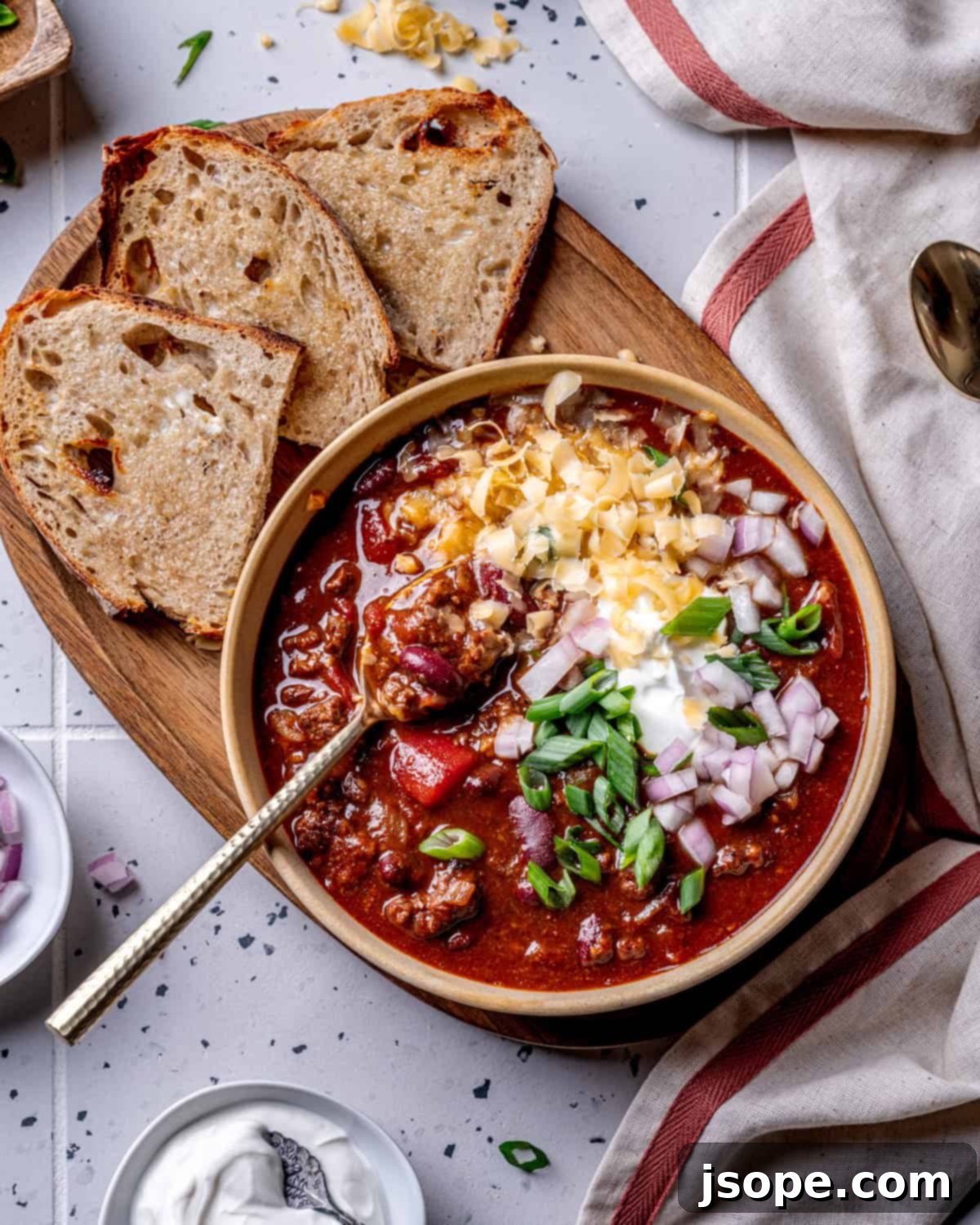 A bowl of Chili with Kidney Beans, garnished with sour cream and green onions.