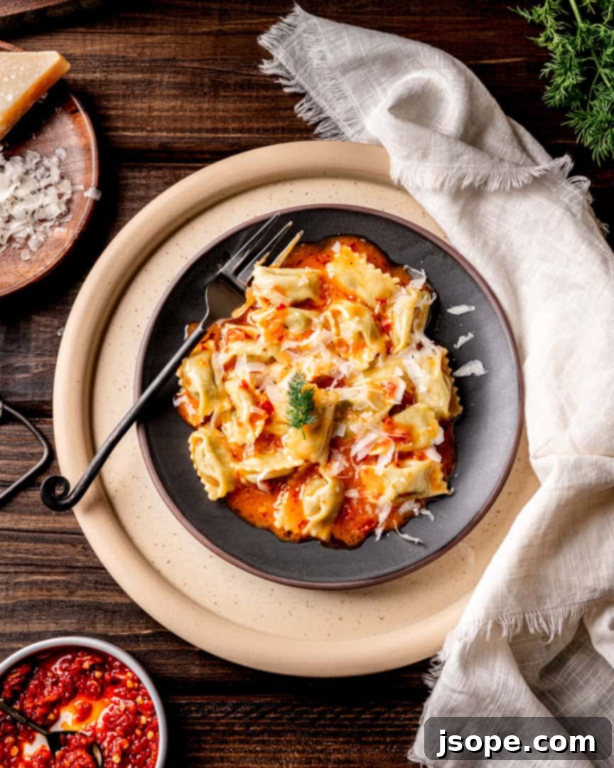 Fava Bean Agnolotti del Plin with Calabrian Chili Butter Sauce, showcasing the vibrant green pasta pillows in a rich, spicy butter sauce.