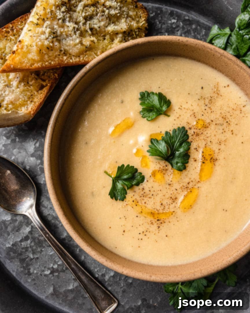 Creamy Potato and Caramelized Leek Soup, being blended to a smooth consistency with an immersion blender.