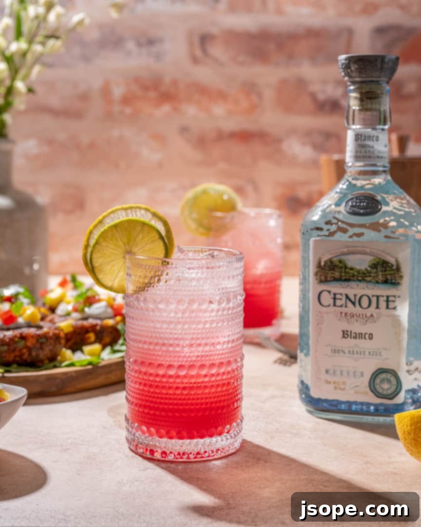 Two glasses of Sparkling Pomegranate Ranch Water, brightly colored, with lemon and lime garnishes, suggesting a refreshing drink for warm weather.