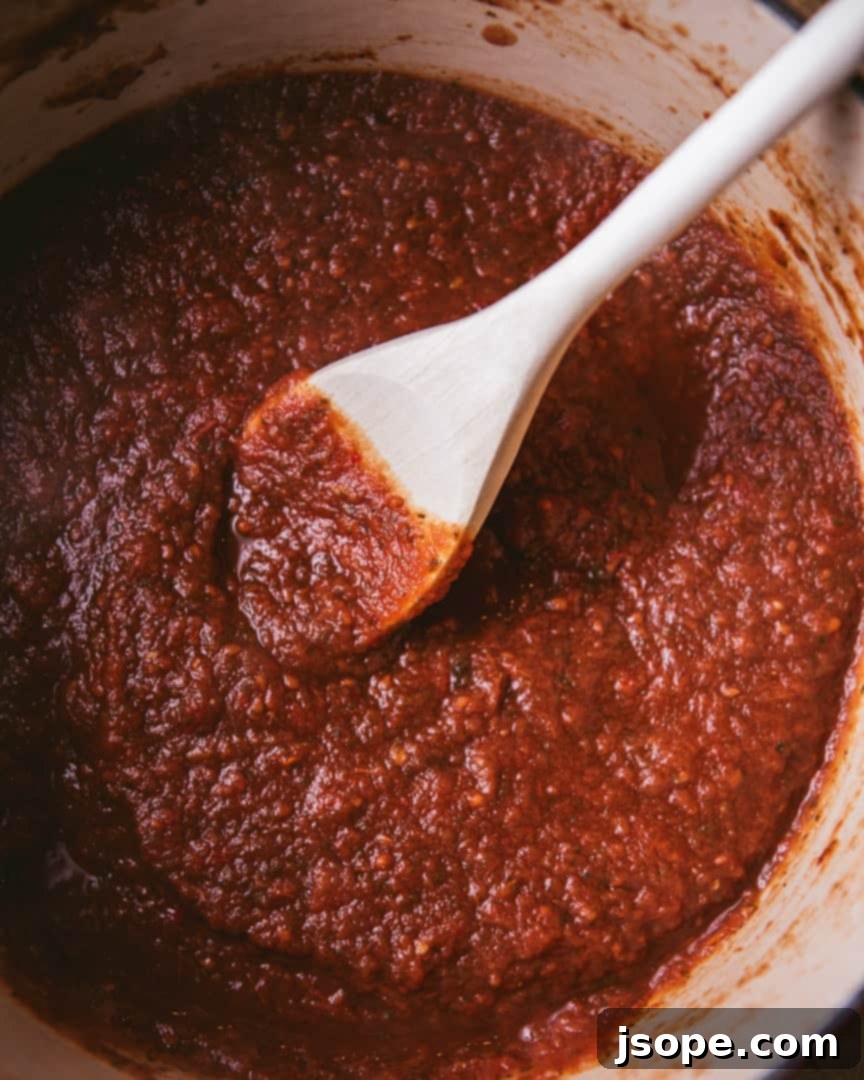 Homemade Marinara Sauce from Scratch: A close-up of a rich, red marinara sauce simmering in a pot, garnished with fresh basil leaves. Perfect for enhancing pasta dishes, meatballs, or pizza.